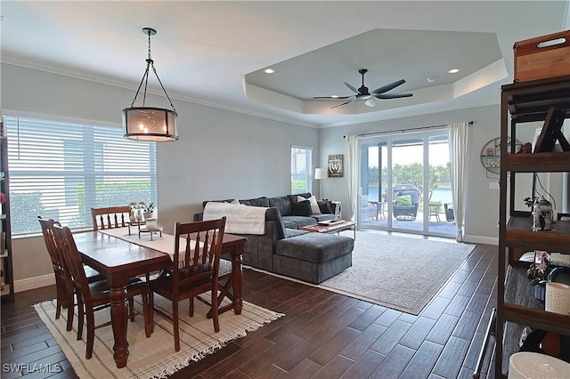 dining space featuring wood finish floors, a tray ceiling, baseboards, and crown molding