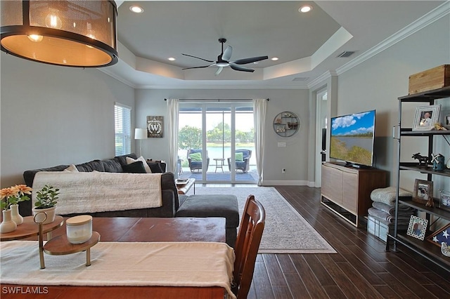 living area featuring visible vents, ornamental molding, baseboards, a raised ceiling, and dark wood-style flooring