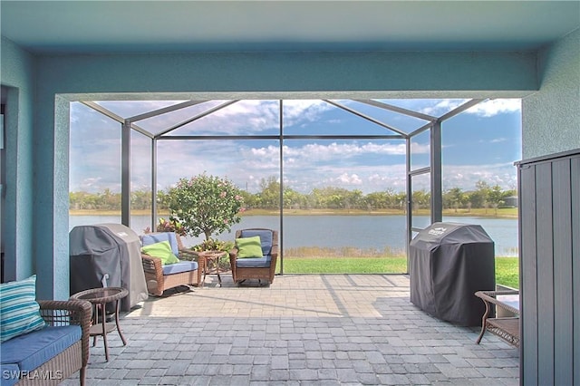 view of patio / terrace featuring glass enclosure, a grill, and a water view