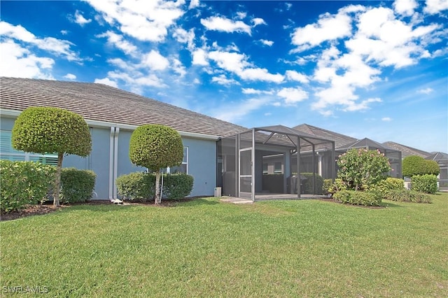 back of property featuring stucco siding, a lawn, and a lanai