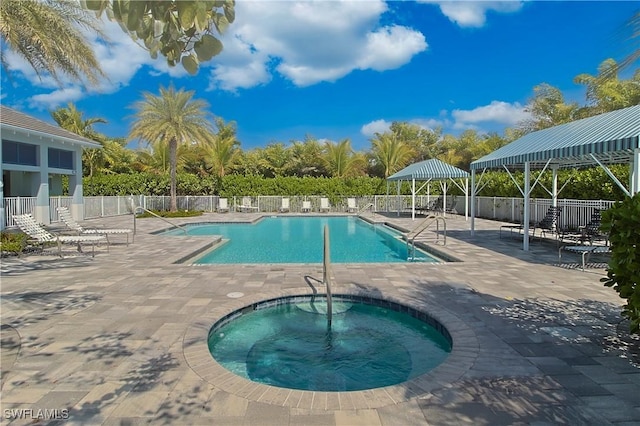 community pool featuring a patio, fence, and a hot tub