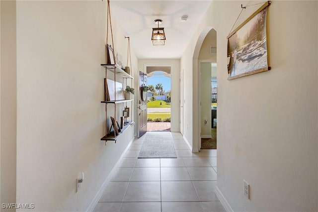 entryway with light tile patterned floors, baseboards, arched walkways, and visible vents