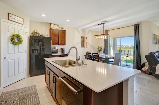 kitchen featuring light tile patterned floors, a sink, black fridge with ice dispenser, stainless steel dishwasher, and decorative light fixtures