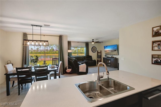 kitchen with ceiling fan with notable chandelier, a sink, decorative light fixtures, light countertops, and dishwasher