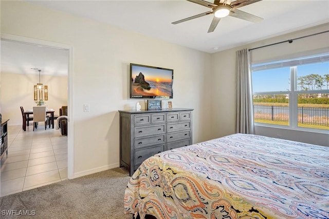 bedroom with light tile patterned floors, light colored carpet, baseboards, and ceiling fan