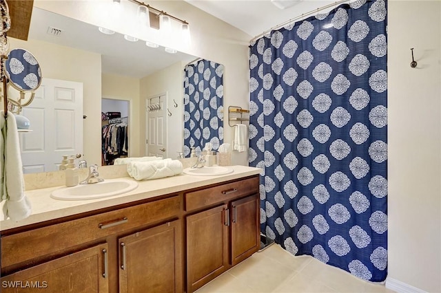 bathroom featuring tile patterned flooring, double vanity, a shower with curtain, and a sink