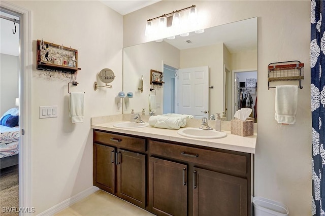 ensuite bathroom featuring double vanity, ensuite bathroom, baseboards, and a sink