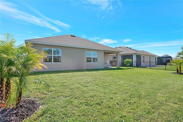 rear view of house featuring stucco siding, a yard, and fence