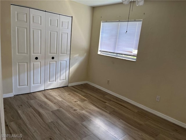 unfurnished bedroom with a closet, baseboards, and wood finished floors