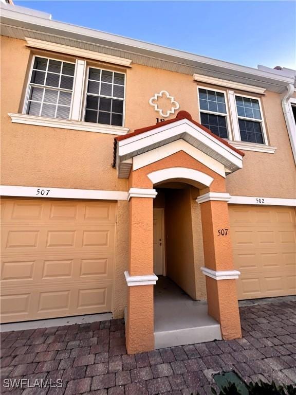 multi unit property featuring an attached garage and stucco siding