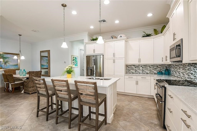 kitchen with visible vents, a kitchen island with sink, a sink, backsplash, and appliances with stainless steel finishes