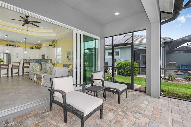 sunroom / solarium with a raised ceiling and ceiling fan