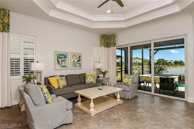 living area with ceiling fan, a tray ceiling, and ornamental molding