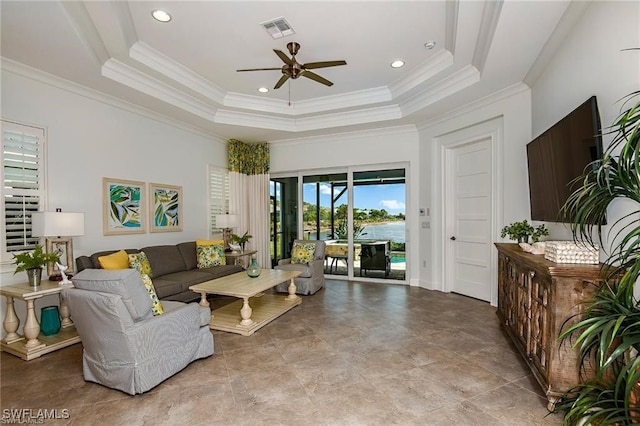 living area featuring a tray ceiling, crown molding, visible vents, and ceiling fan