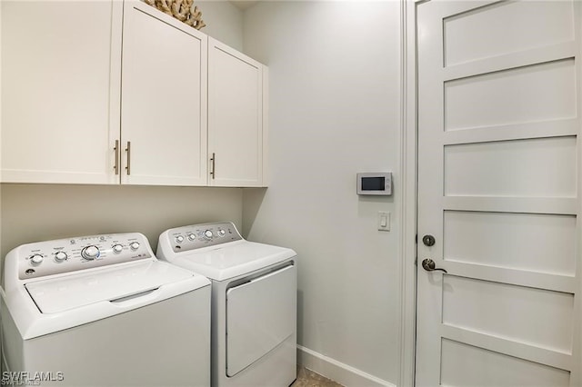 clothes washing area featuring cabinet space, baseboards, and washer and clothes dryer