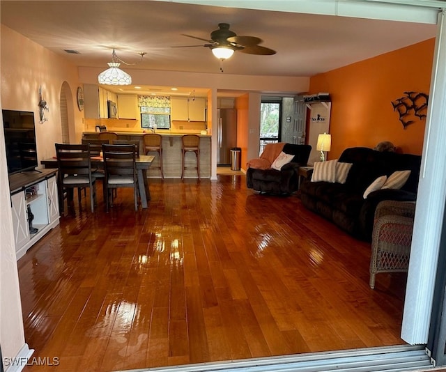 living area with arched walkways, dark wood-style flooring, and ceiling fan