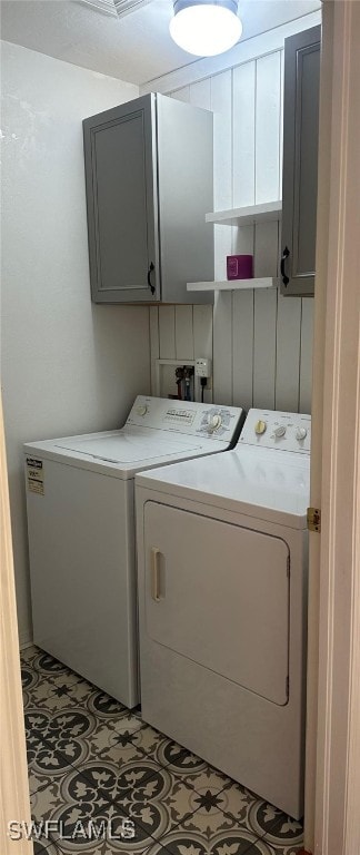 clothes washing area with cabinet space, independent washer and dryer, and tile patterned flooring