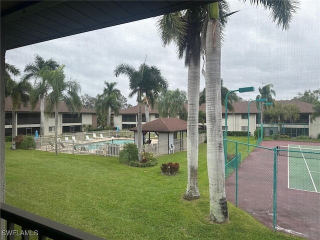 view of community featuring a pool, a yard, and fence