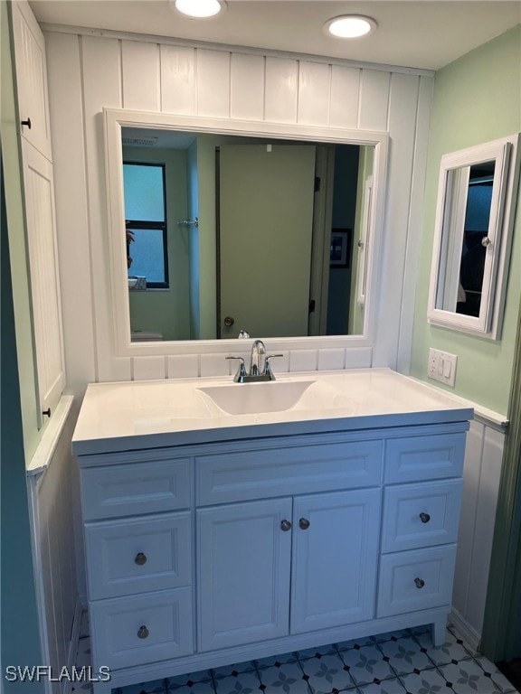 bathroom featuring vanity, tile patterned floors, and a decorative wall