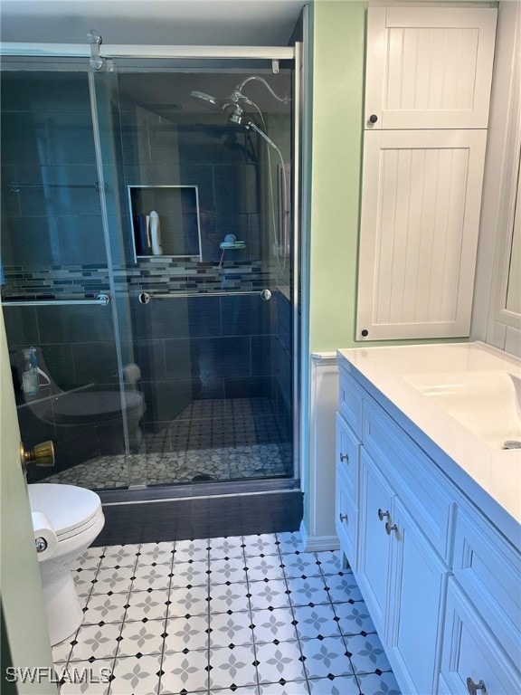 bathroom with a shower stall, toilet, and vanity