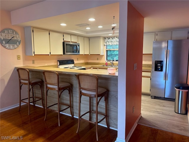 kitchen featuring visible vents, light wood-style flooring, recessed lighting, appliances with stainless steel finishes, and a raised ceiling