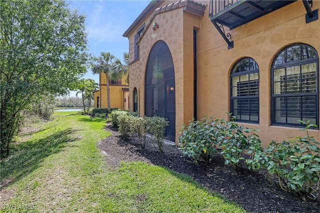 view of side of property with a lawn and stucco siding