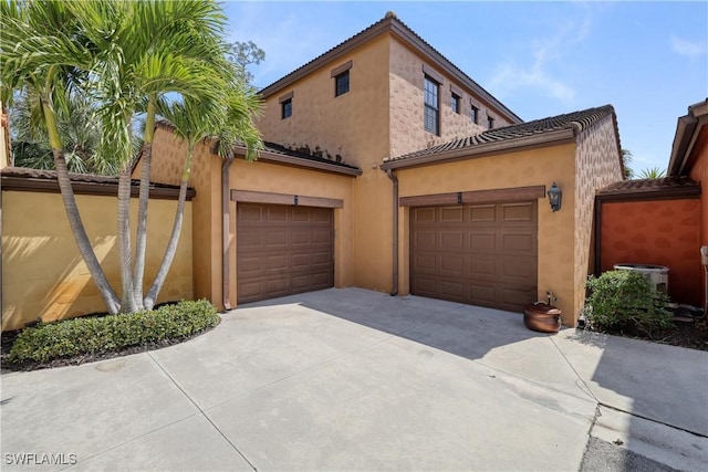 mediterranean / spanish house with central air condition unit, stucco siding, concrete driveway, and a garage