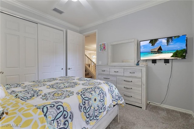 carpeted bedroom with a ceiling fan, baseboards, visible vents, ornamental molding, and a closet