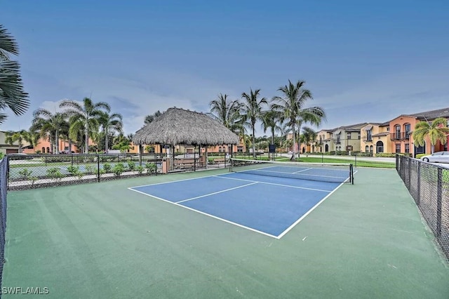 view of tennis court featuring a residential view and fence