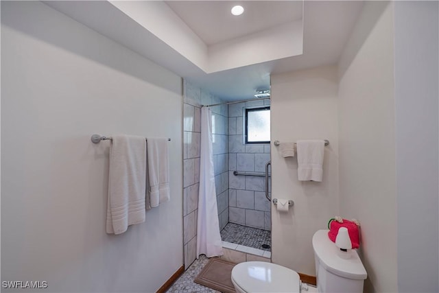 full bath with baseboards, toilet, and a tile shower