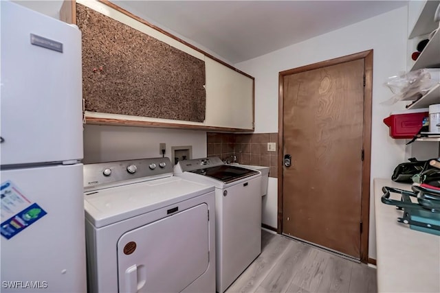 laundry area featuring cabinet space, washer and dryer, and light wood-type flooring