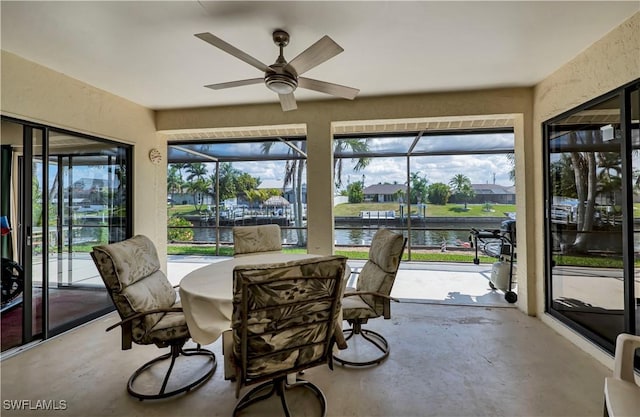 sunroom featuring a healthy amount of sunlight, ceiling fan, and a water view