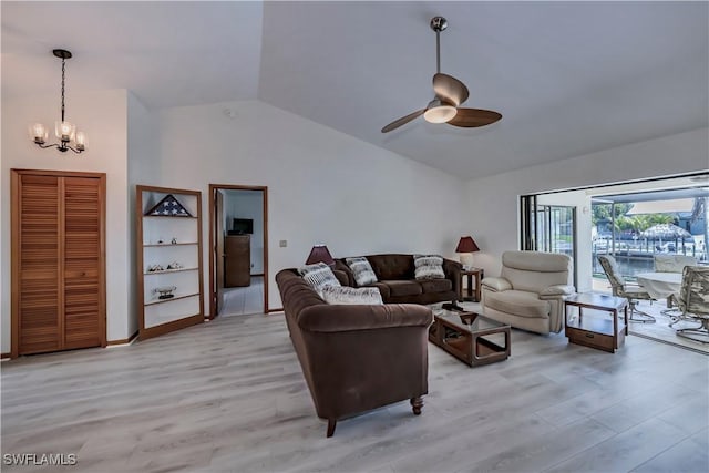 living area featuring baseboards, high vaulted ceiling, light wood-style flooring, and ceiling fan with notable chandelier