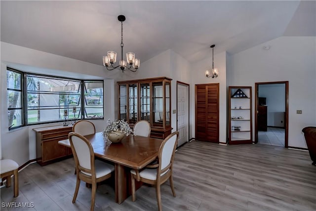 dining area featuring baseboards, lofted ceiling, a chandelier, and light wood finished floors