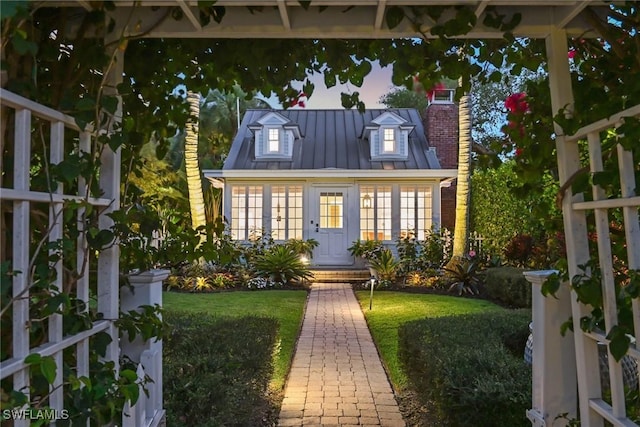 rear view of property featuring a standing seam roof, metal roof, a lawn, and a chimney