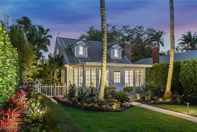 view of home's exterior with a standing seam roof, fence, a lawn, and metal roof