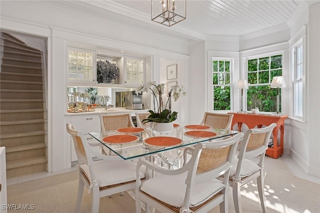 dining space with stairs, a notable chandelier, light colored carpet, and crown molding