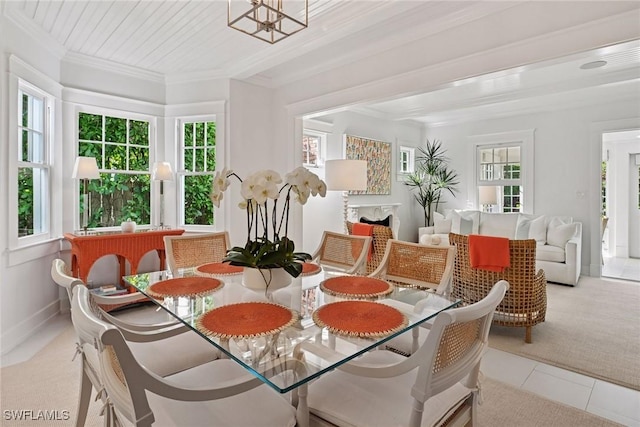 carpeted dining room with tile patterned floors, a healthy amount of sunlight, a fireplace, and crown molding