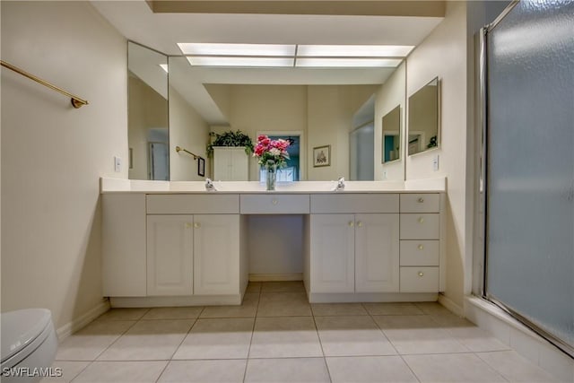 full bathroom featuring double vanity, toilet, a stall shower, and a sink