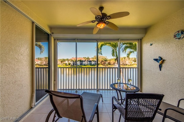 sunroom with a ceiling fan and a water view