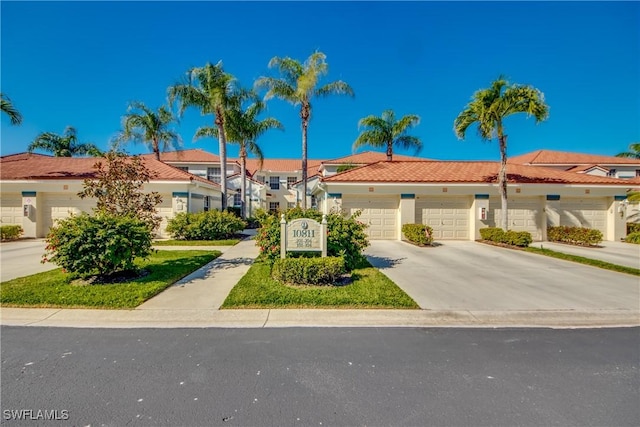 multi unit property featuring driveway, an attached garage, stucco siding, a tiled roof, and a residential view