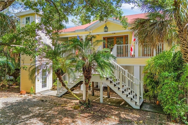 raised beach house featuring covered porch and stairs