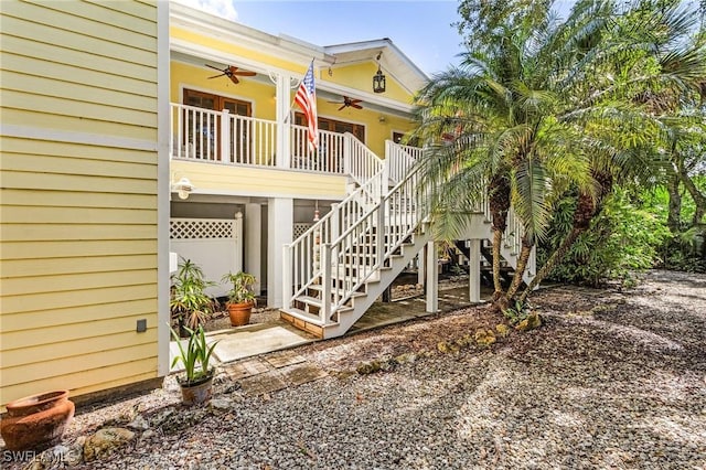 view of side of property featuring covered porch, ceiling fan, and stairs