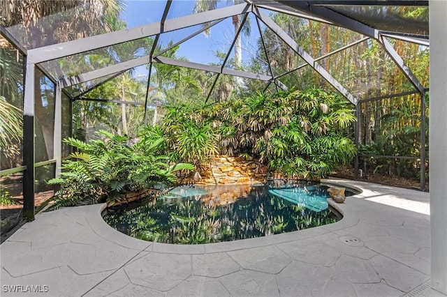 outdoor pool featuring glass enclosure and a patio