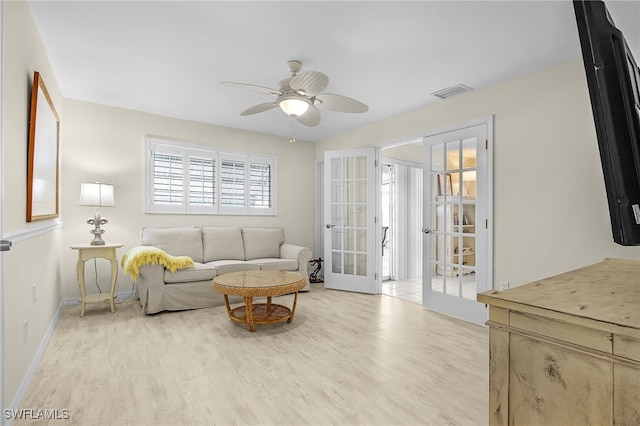 living area with baseboards, visible vents, light wood-style flooring, ceiling fan, and french doors