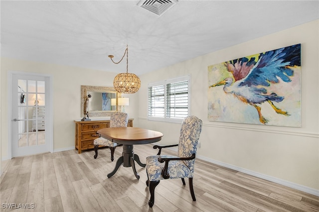 dining area featuring baseboards, light wood-style floors, visible vents, and a chandelier