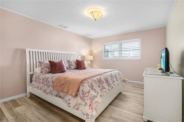 bedroom with baseboards, light wood-style flooring, and crown molding