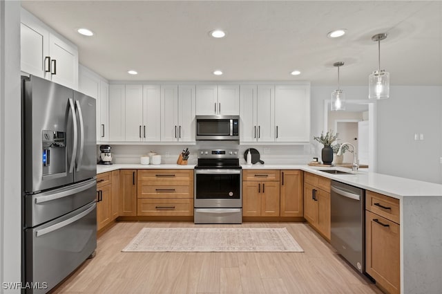 kitchen with a sink, a peninsula, light countertops, and stainless steel appliances