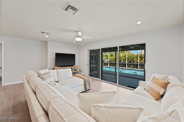 living room featuring visible vents, wood finished floors, and a sunroom