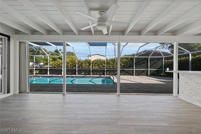 pool with glass enclosure, a patio area, and a ceiling fan